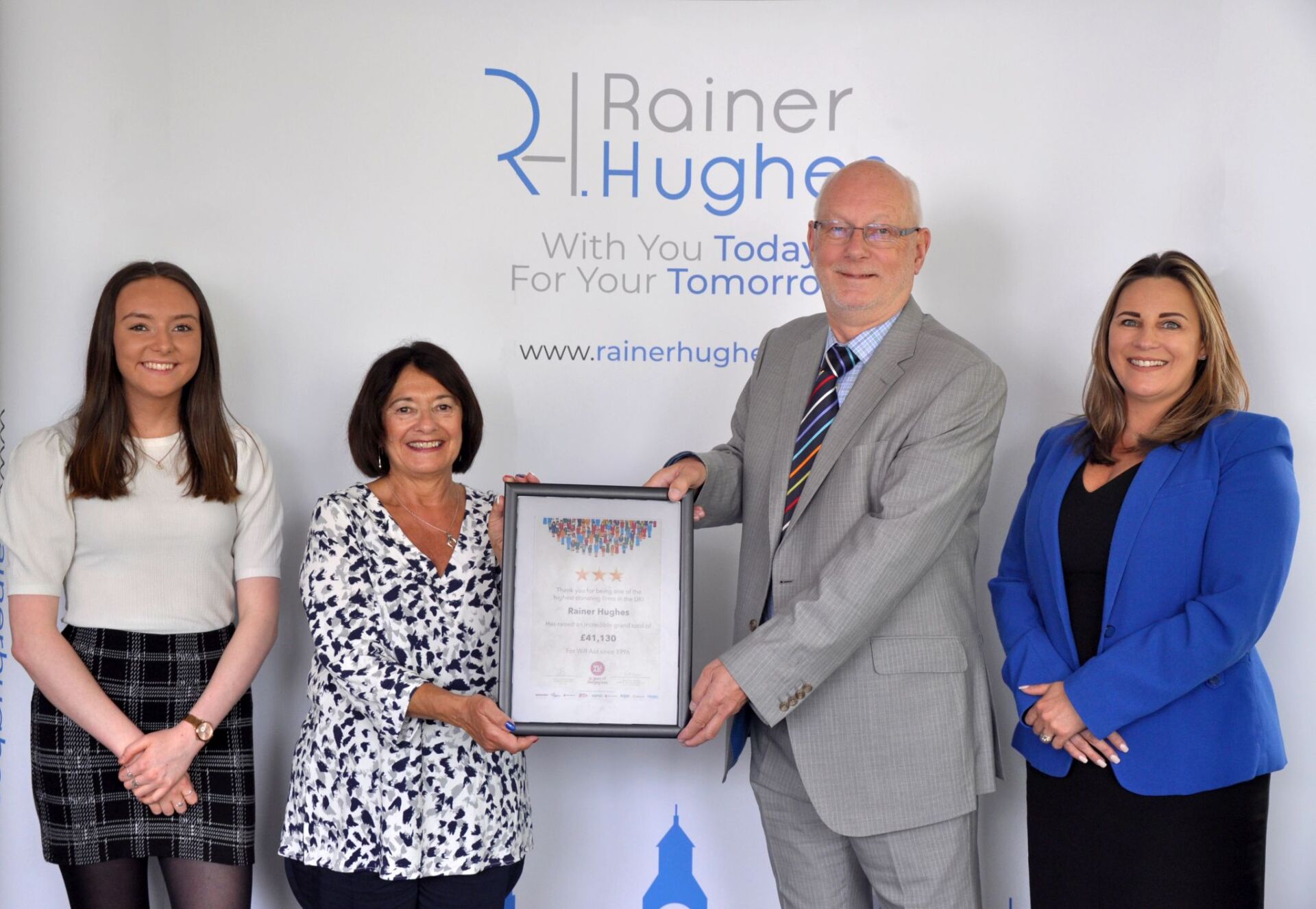 A group of people standing in front of a banner that says rainer hughes