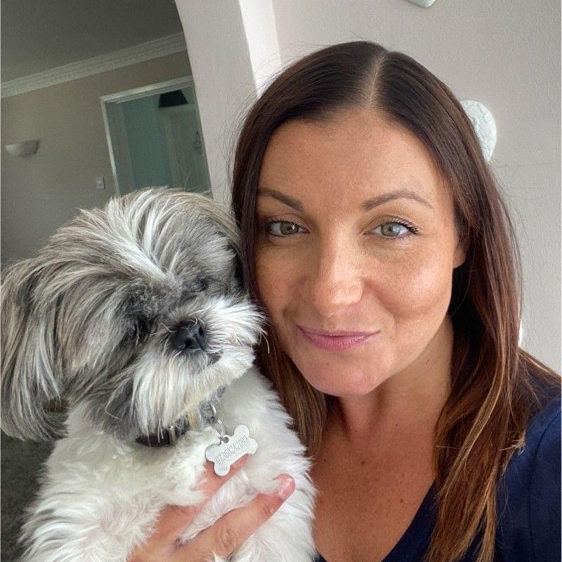 A woman is holding a small dog in her arms