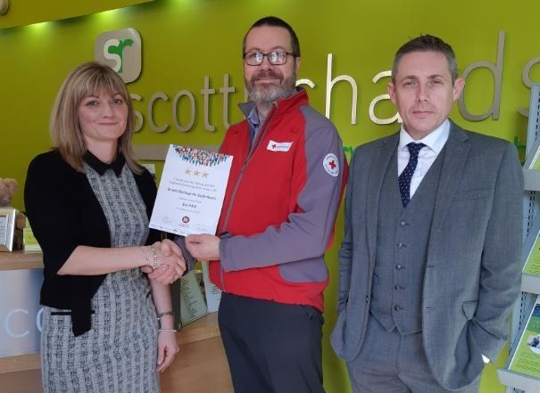 A man in a red vest is shaking hands with a woman