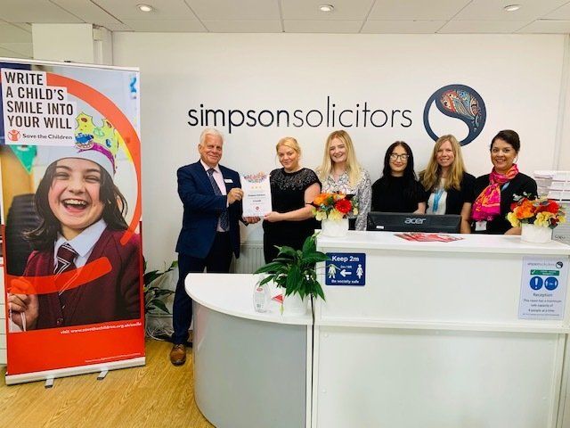 A group of people standing in front of a sign that says simpson solicitors
