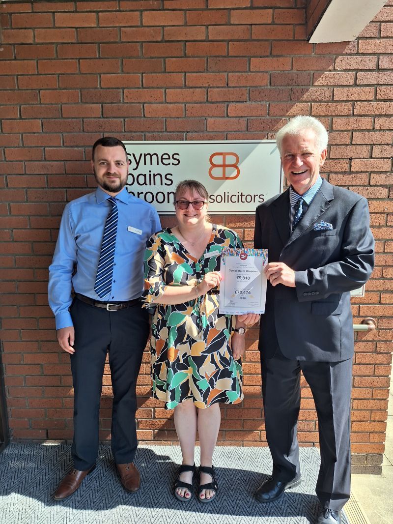 Two men and a woman are posing for a picture in front of a brick building.