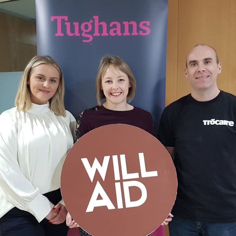 Three people holding a sign that says will aid