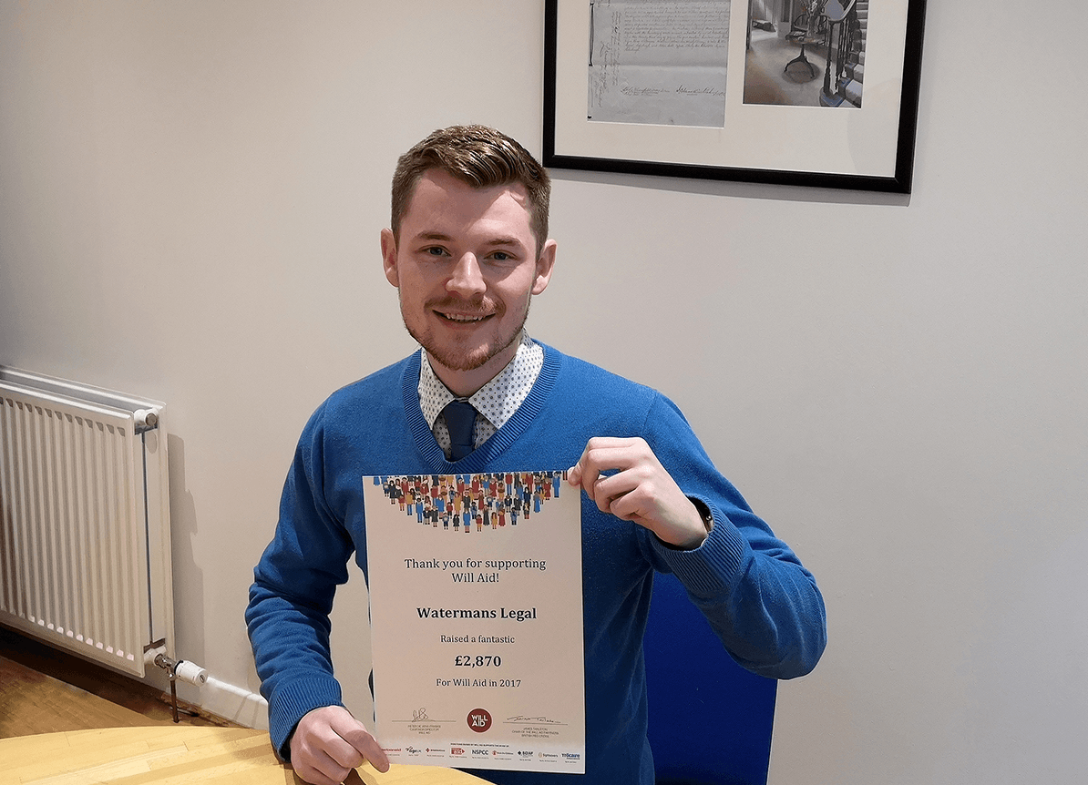 A man in a blue sweater and tie is holding a certificate.