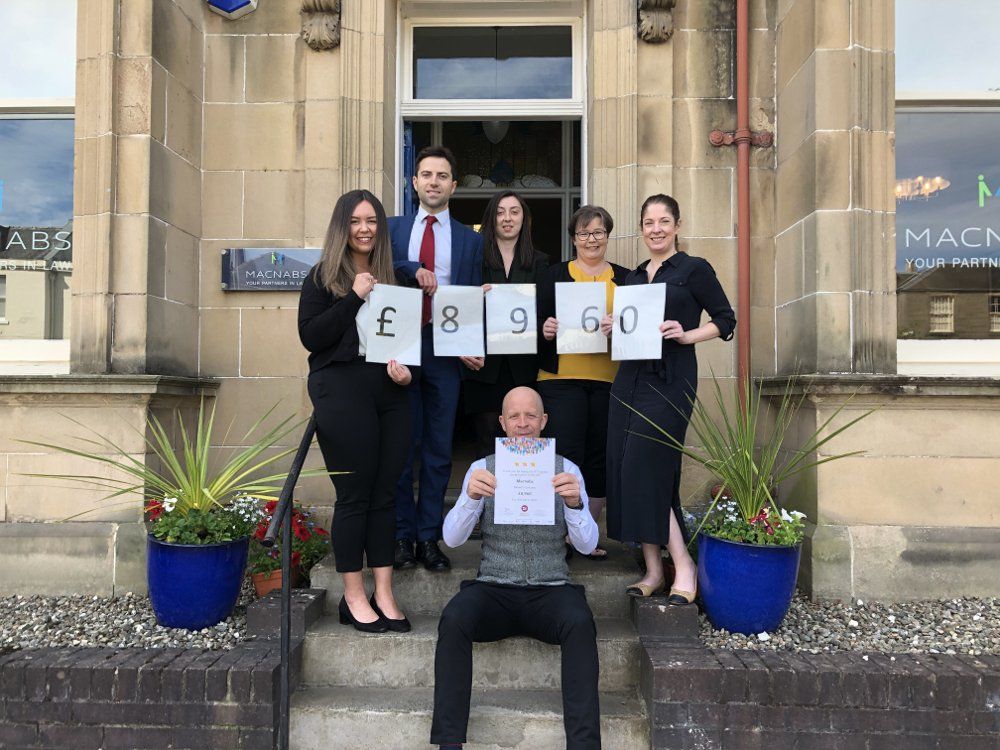 A group of people standing on the steps of a building holding signs.