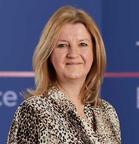 A woman in a leopard print shirt is smiling for the camera.