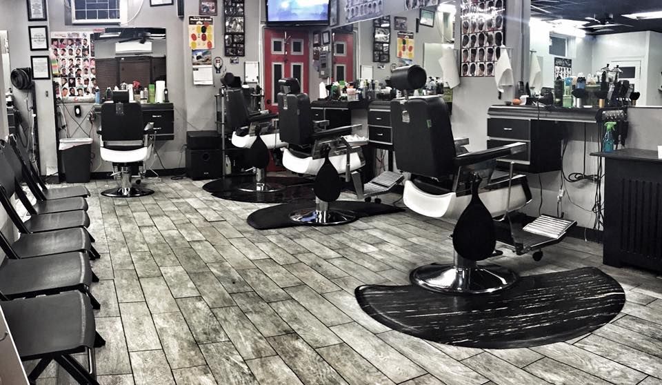 Empty modern barbershop with black chairs, mirrors, and patterned wood flooring