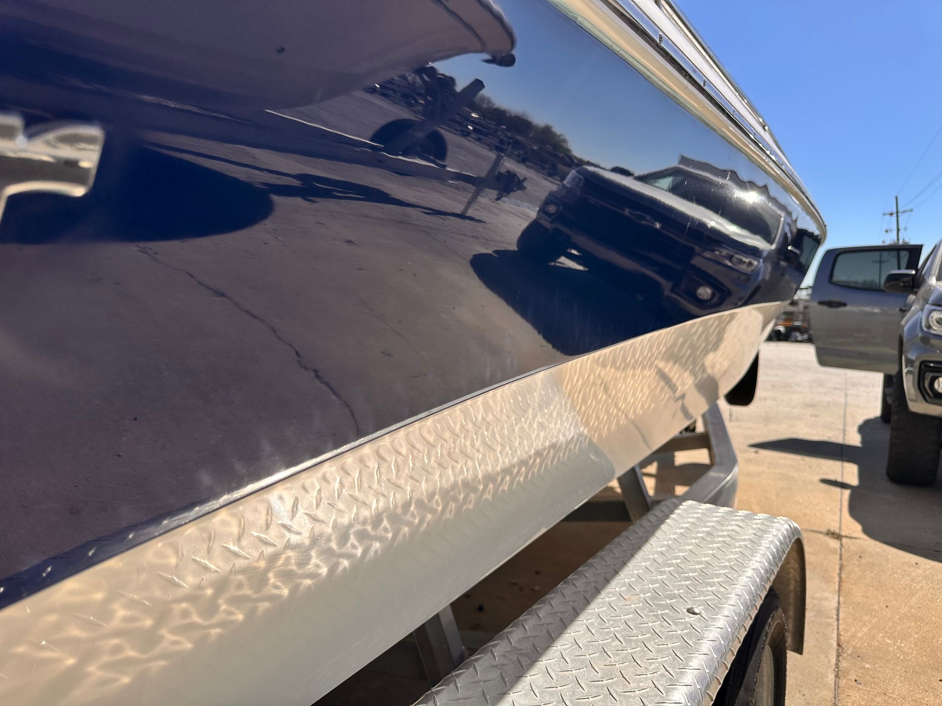 Blue boat on a trailer, reflected car, silver diamond plate trim.