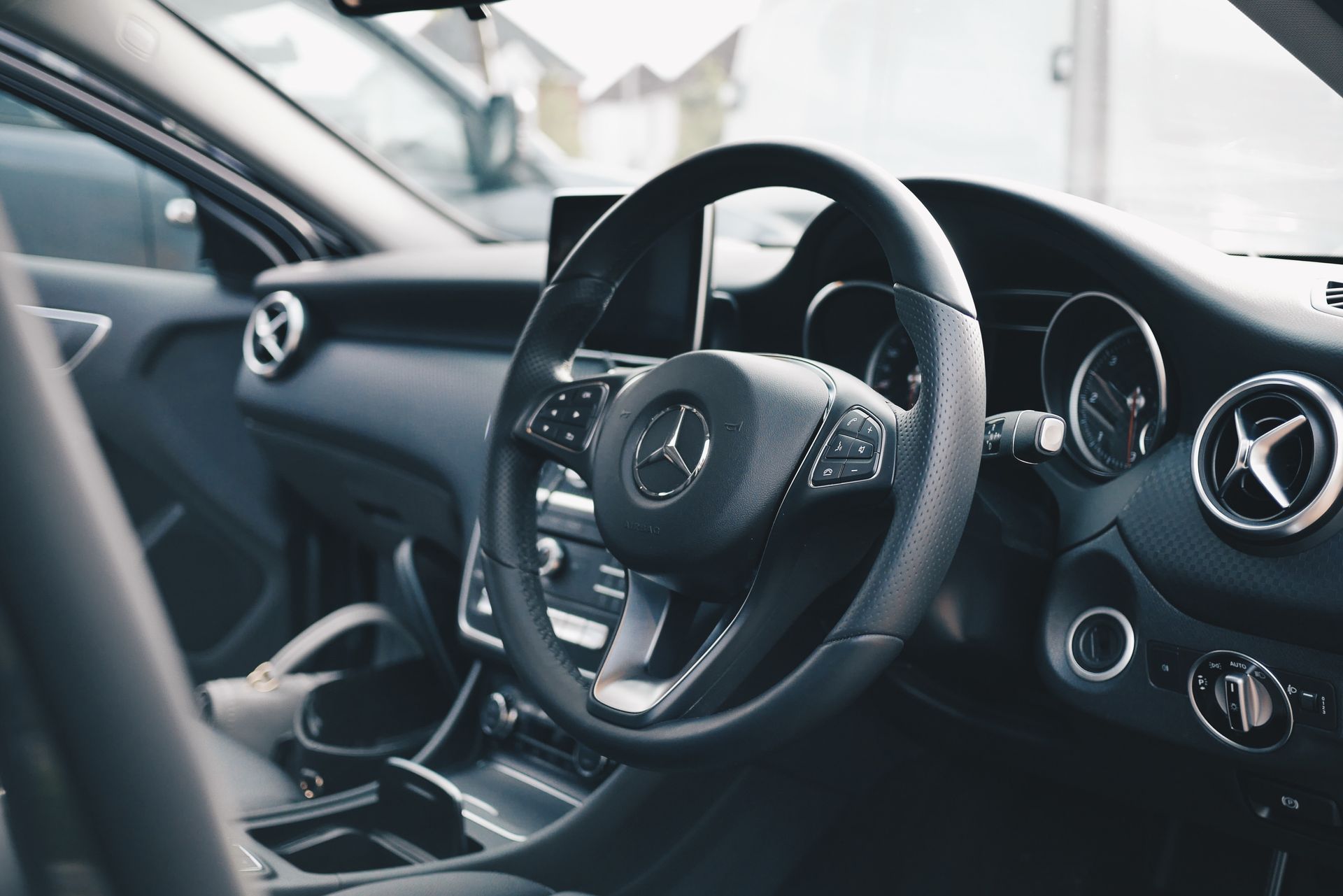 Interior view of a Mercedes-Benz car: dashboard, steering wheel with logo, and air vents.