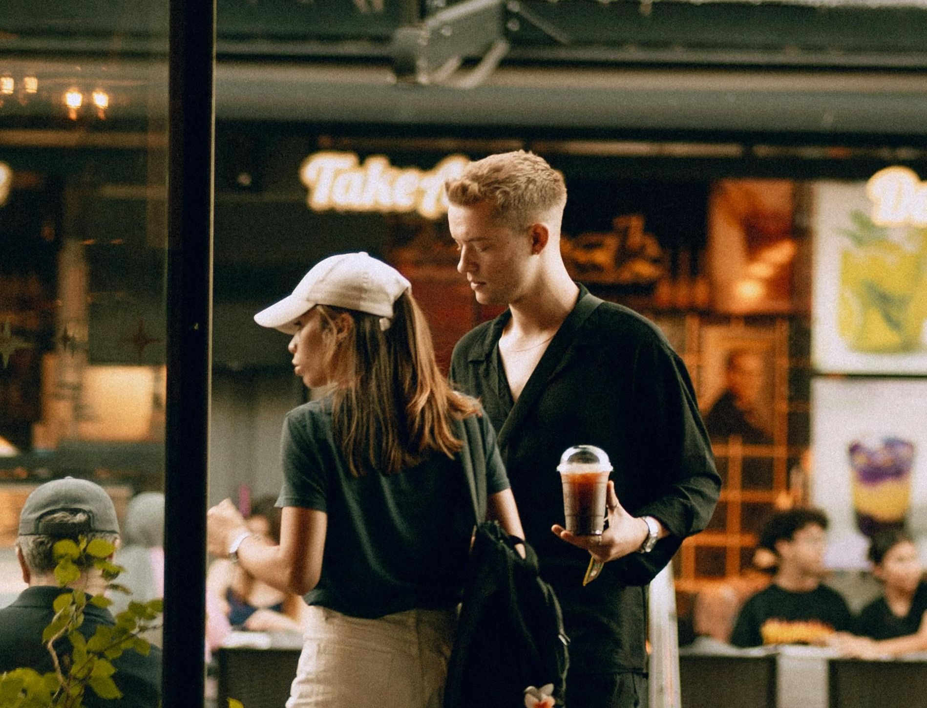 A man and a woman are standing in front of a restaurant.