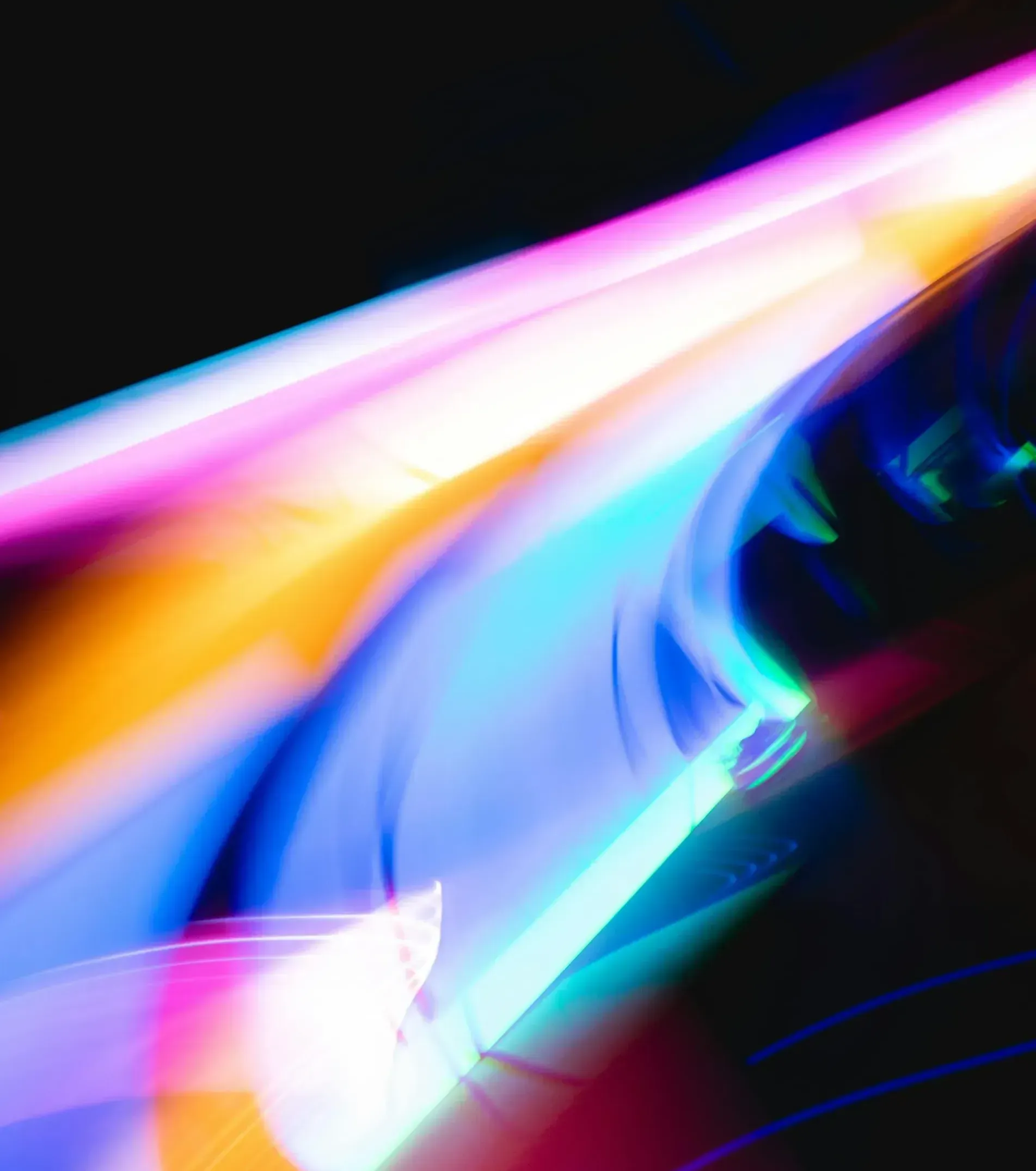 A blurry picture of a rainbow of lights on a black background.