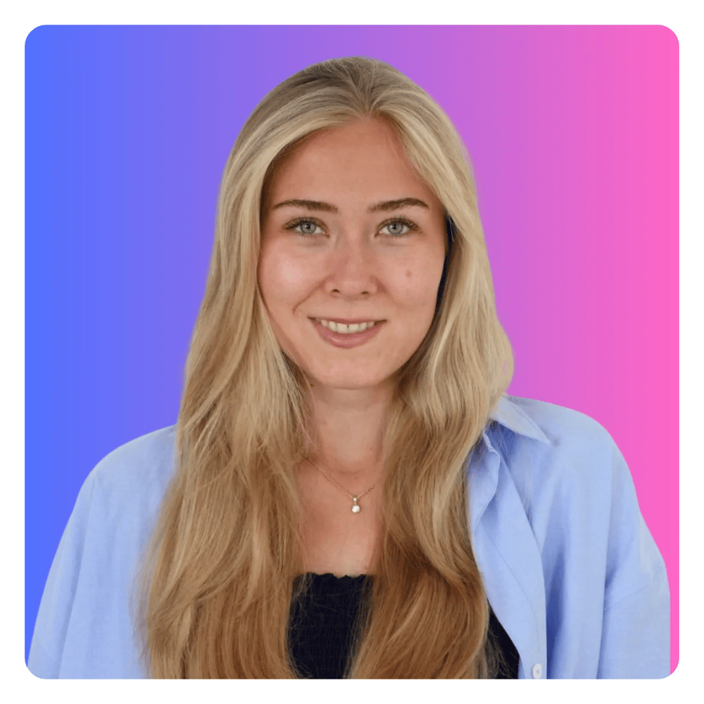 A woman with long blonde hair is wearing a blue shirt and a necklace.