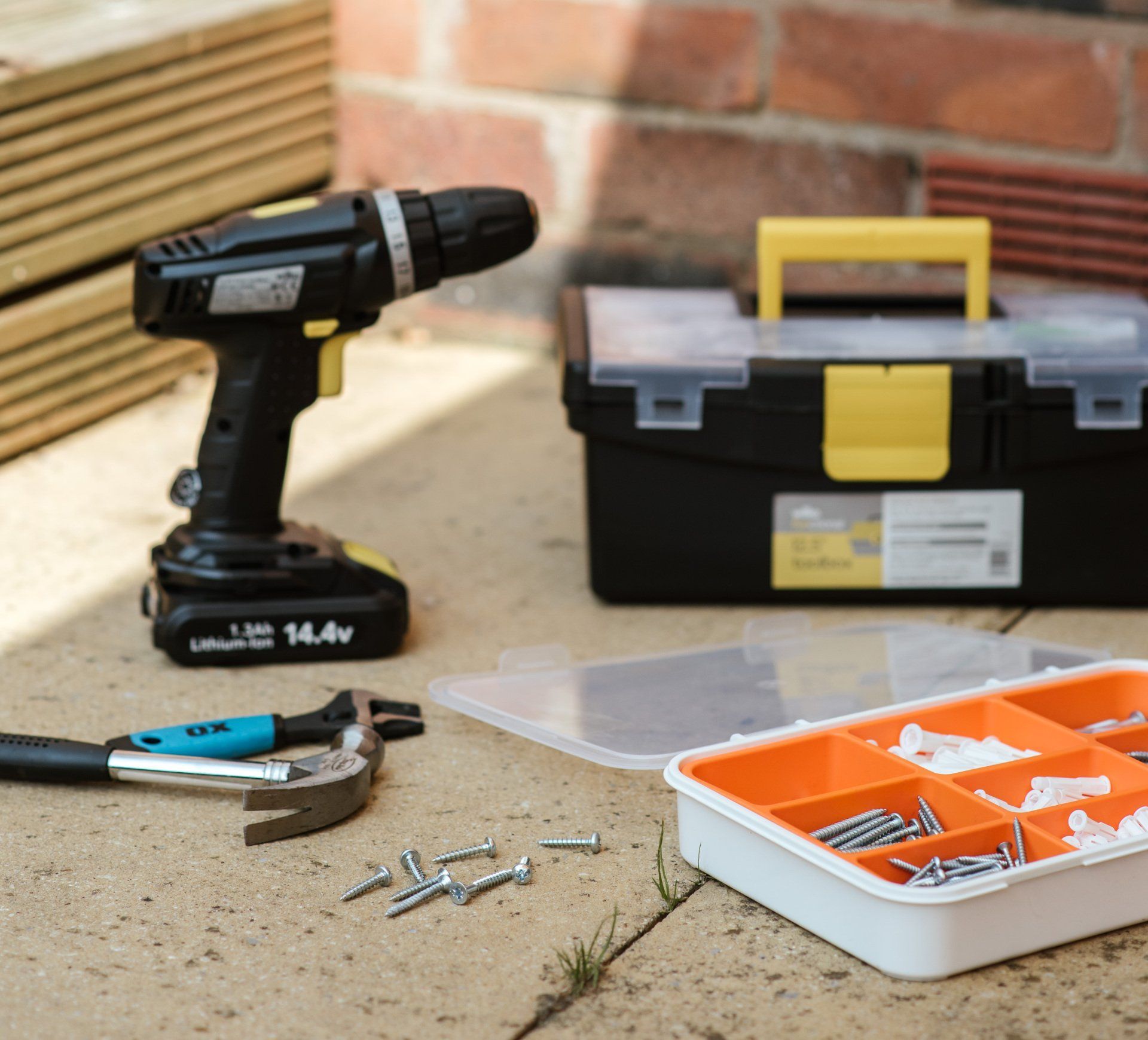 A 14.4v cordless drill sits next to a toolbox