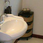 A bathroom sink with a wicker basket next to it.
