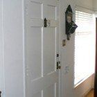 A white door with a clock on the wall next to a window.