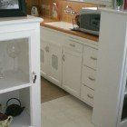 A kitchen with white cabinets , drawers , a sink and a microwave.