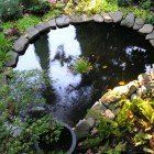 A small pond surrounded by rocks and plants in a garden.