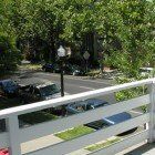 A view of a street from a balcony with a white railing.