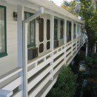 A white house with a long porch and a lot of windows.