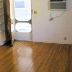 An empty room with hardwood floors and a window air conditioner.