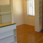 An empty room with hardwood floors , shelves and a window.