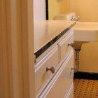 A bathroom with a sink , toilet and dresser.