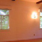 An empty room with two windows and a light on the wall.