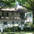 A large white house with a balcony and trees in front of it.