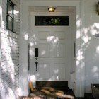 A white door is sitting on a porch next to a window.