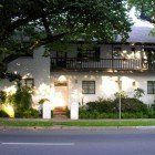 A large white house with a balcony is sitting on the side of the road.