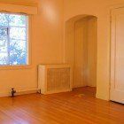 An empty living room with hardwood floors and a window.