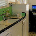 A kitchen with a sink and a computer on the counter.
