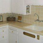 A kitchen with white cabinets , a sink , and a dishwasher.