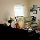 A living room with a couch , chair , and guitar.