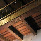 A close up of a wooden ceiling with a staircase in the background.
