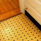 A yellow and black tile floor in a bathroom next to a bathtub.