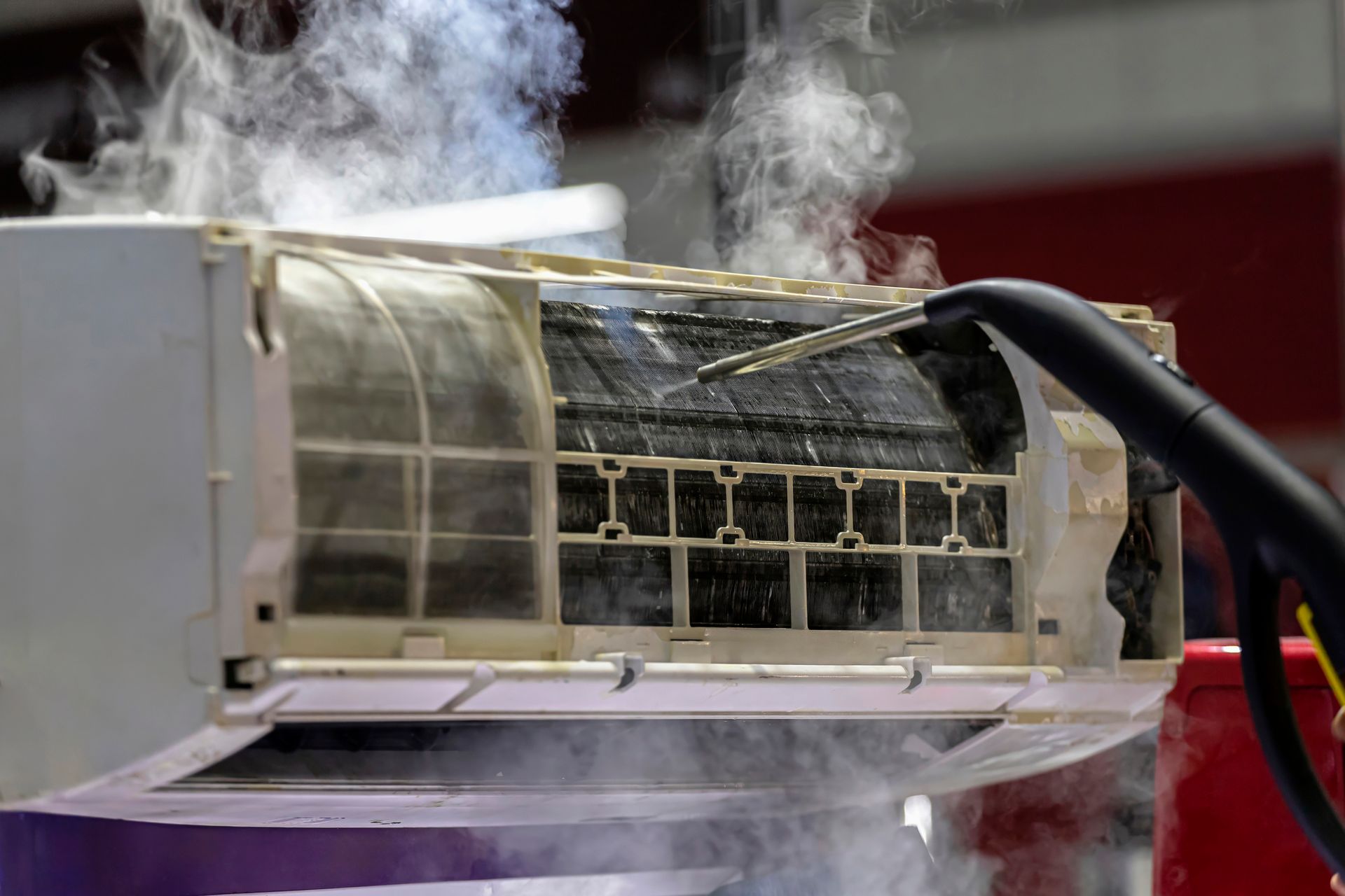 A close up of a dirty air conditioner with steam coming out of it.