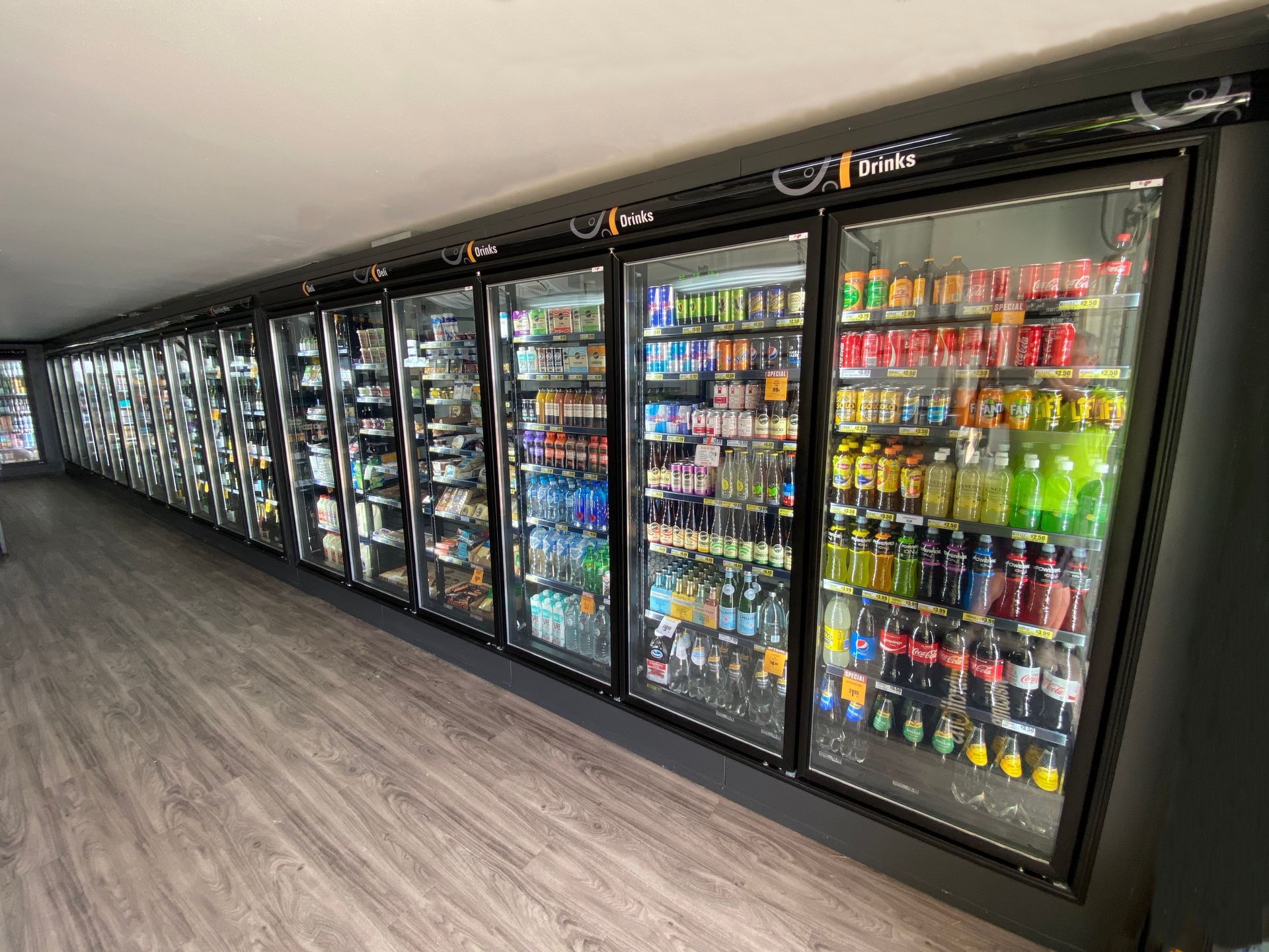 A row of refrigerators filled with lots of drinks in a store.