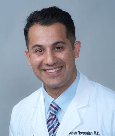 a man in a white lab coat and tie is smiling