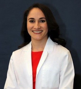 a woman wearing a white lab coat and a red shirt is smiling for the camera