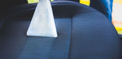 A person is cleaning a car seat with a vacuum cleaner.