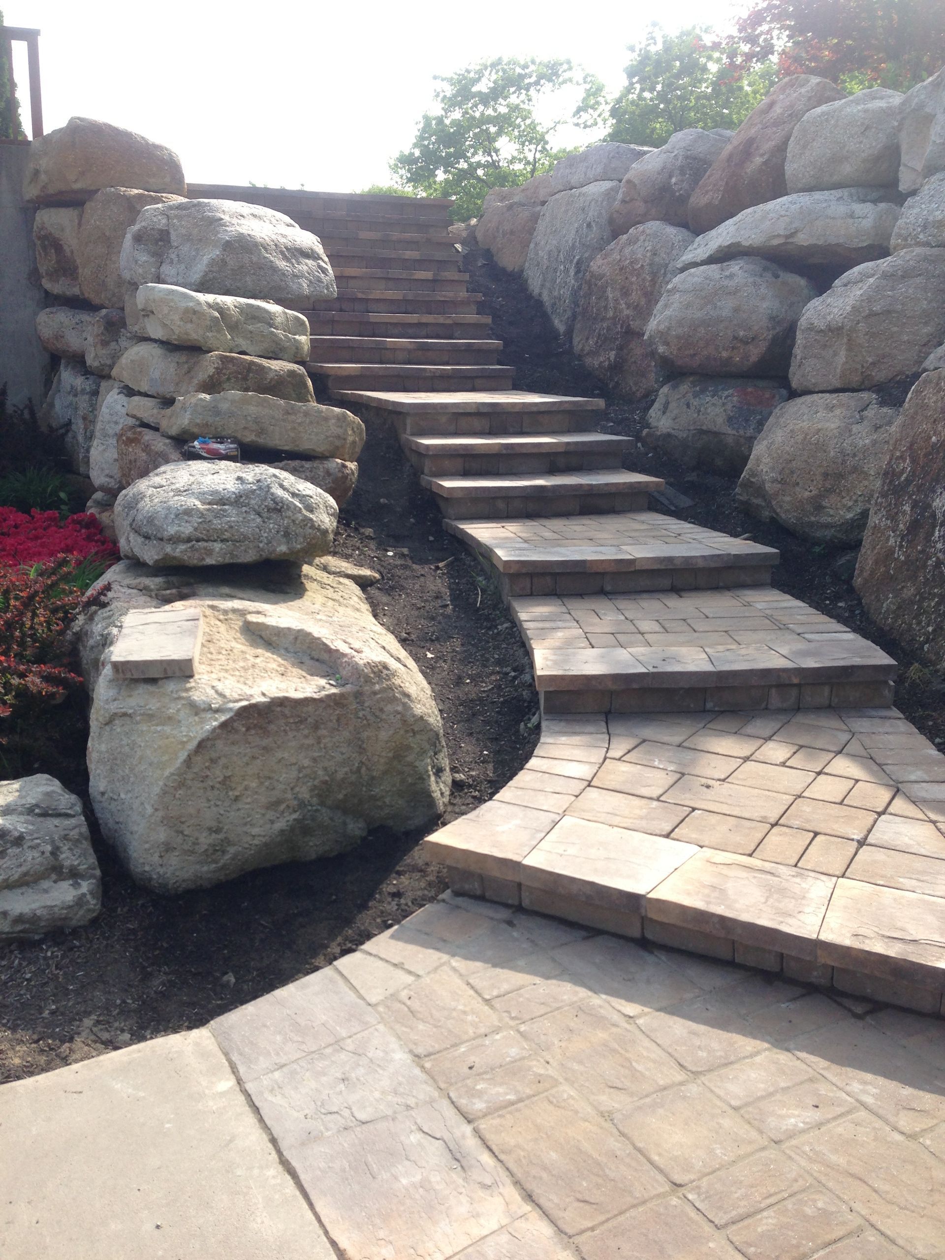 Stone staircase between large boulders in a landscaped garden area