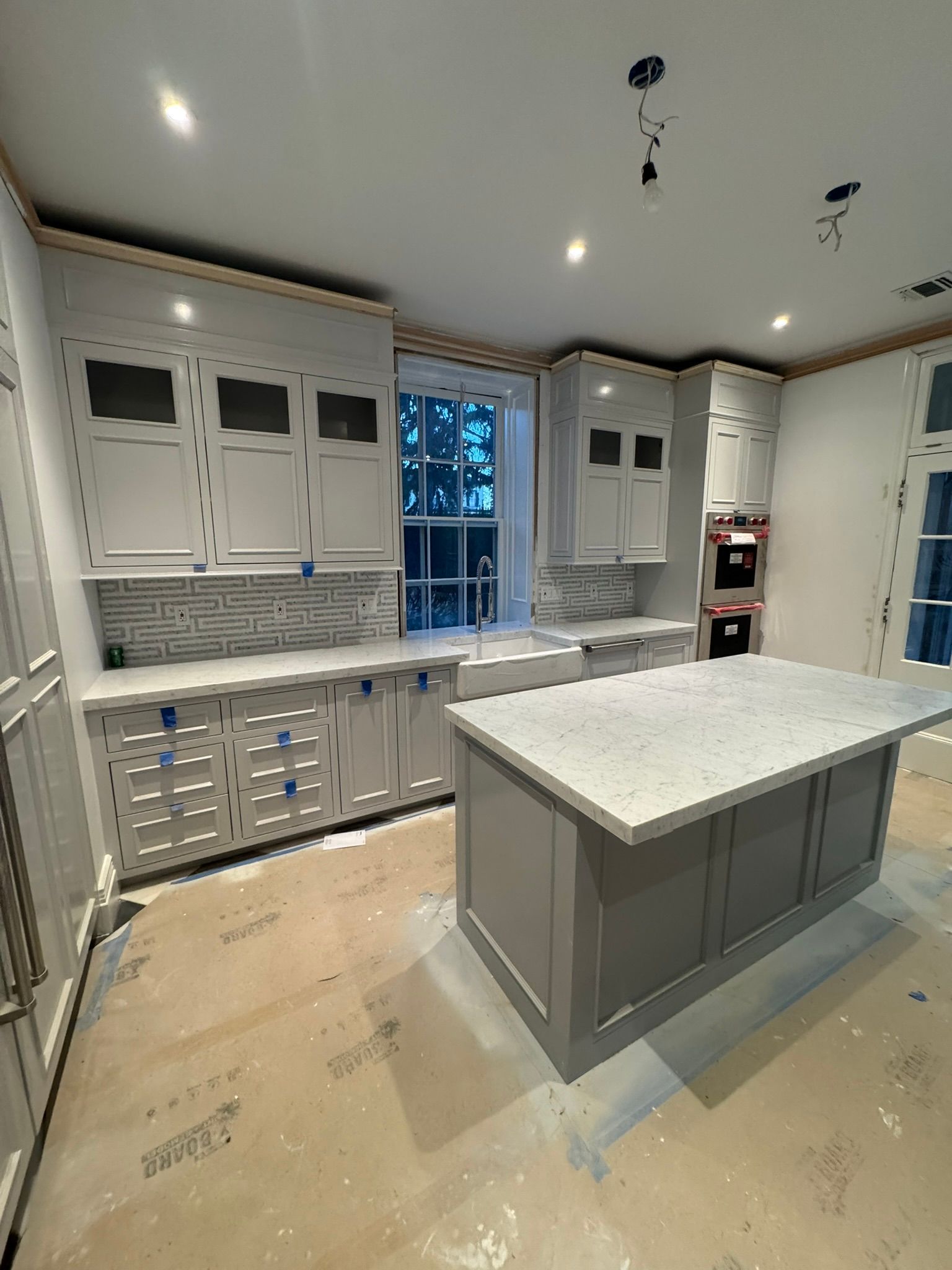 Bright modern kitchen with white cabinets, gray island, and a window centered on the back wall