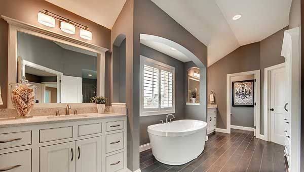 Bright modern bathroom with a freestanding tub, gray walls, white vanity, and dark wood floors