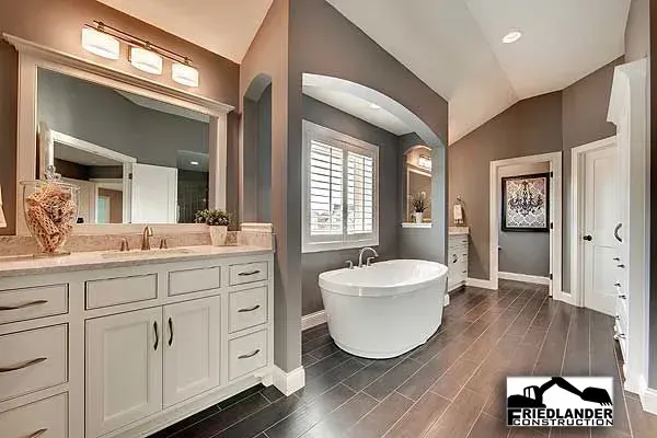 Bright modern bathroom with double vanity, freestanding tub, and gray tile floor