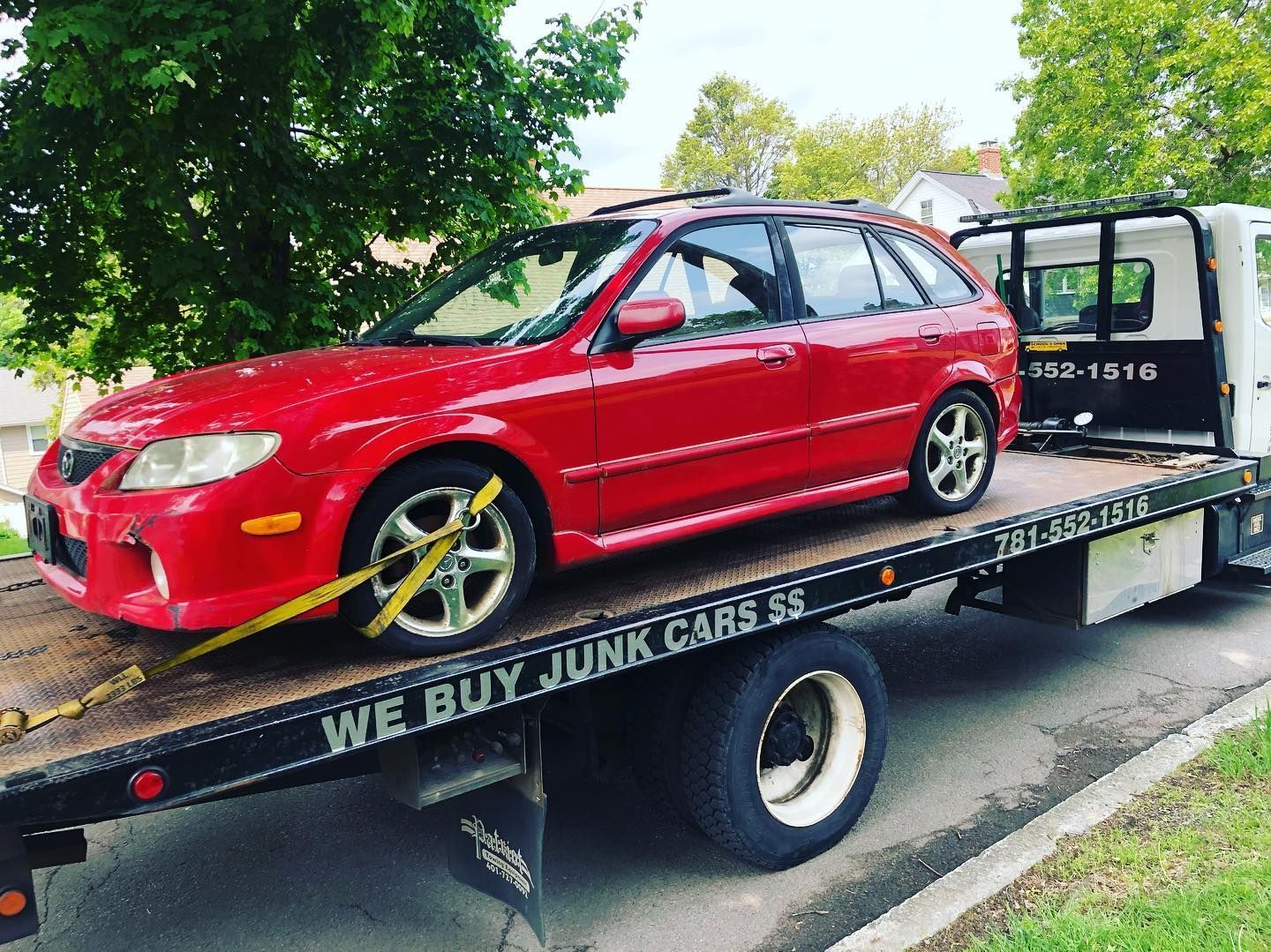 A red car is sitting on top of a tow truck.