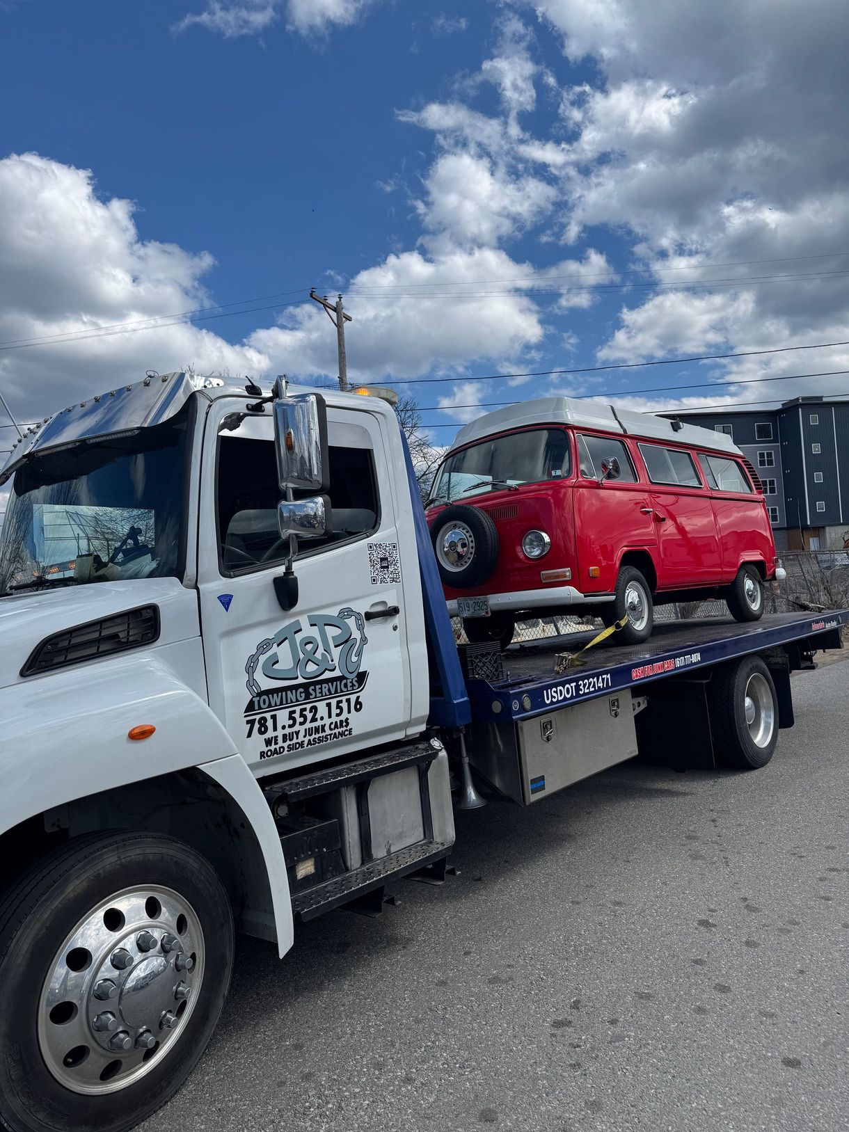 A red van is being towed by a tow truck.