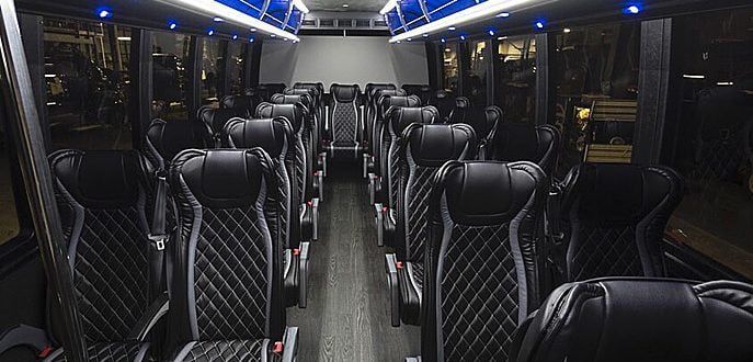 The inside of a large bus with lots of black seats.