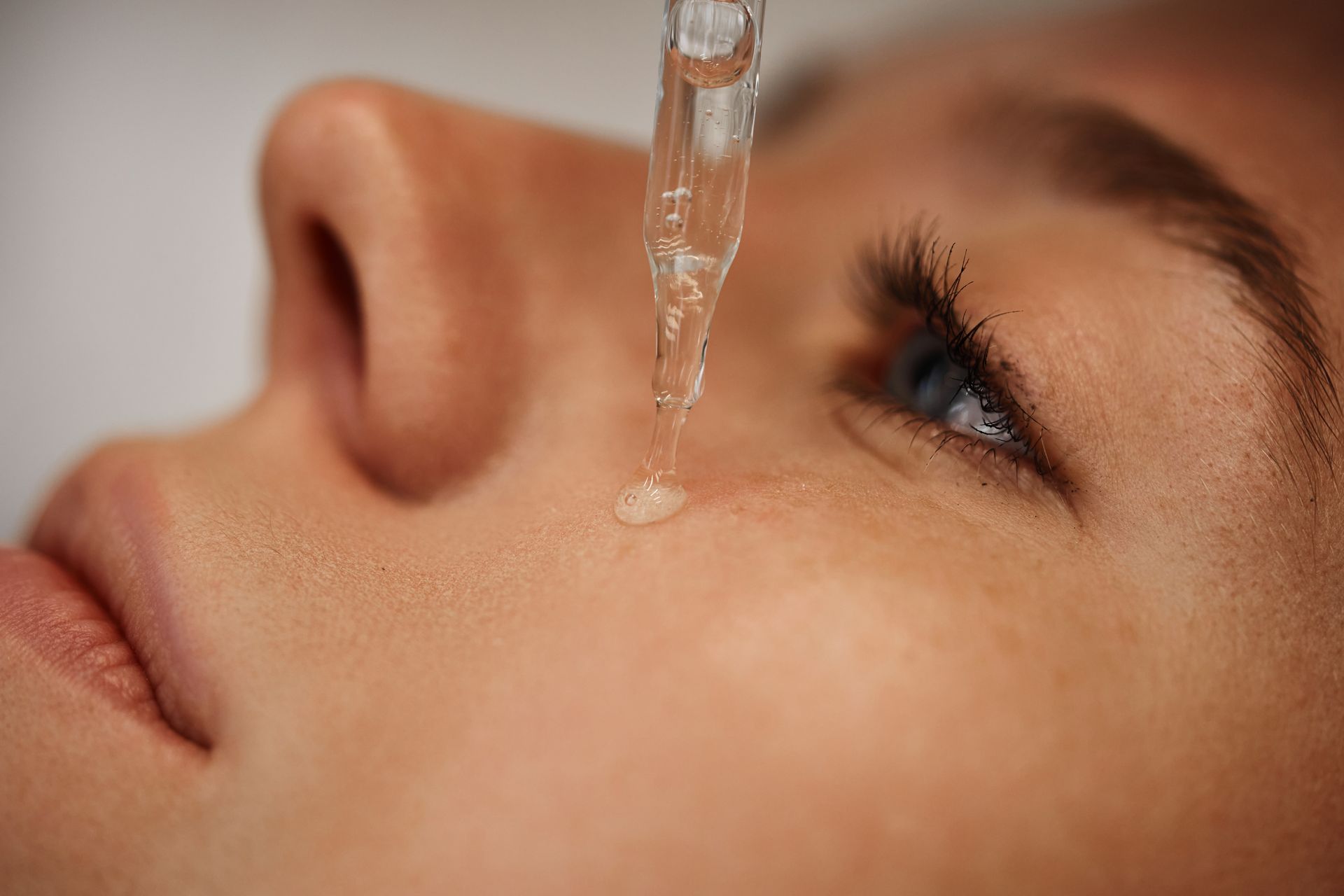 Close-up of a child’s face with a dropper dispensing liquid into the eye