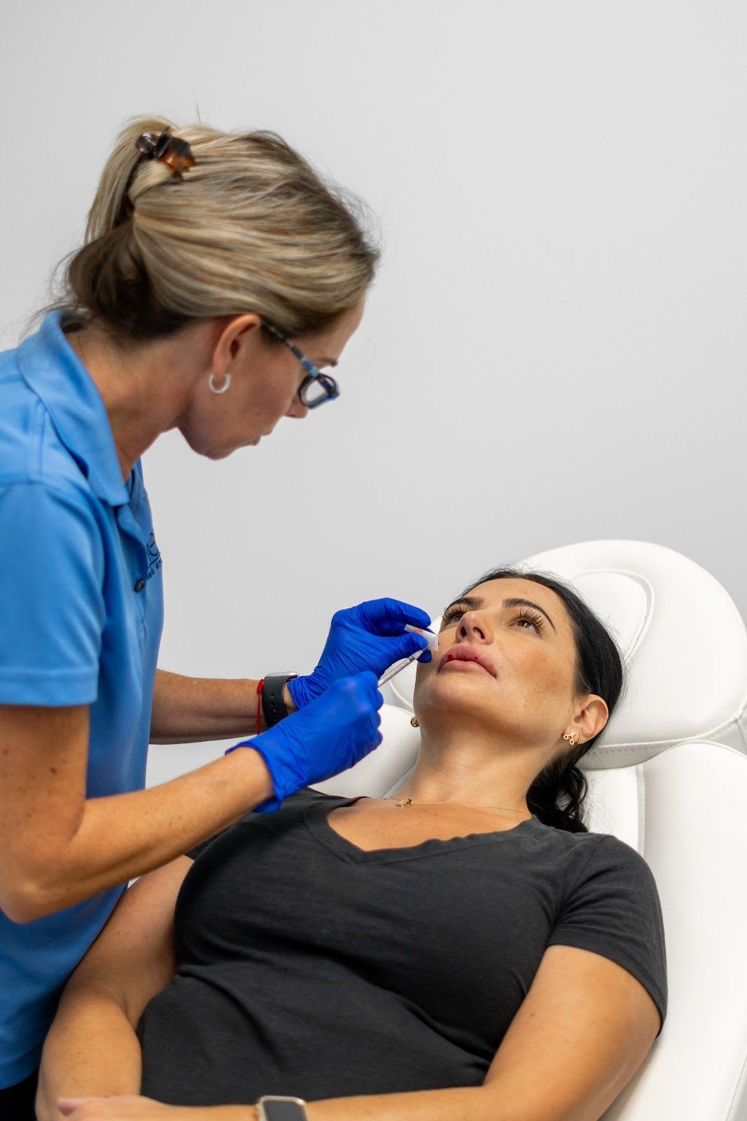 A person receives an IV drip in a medical setting, attended to by a healthcare worker.