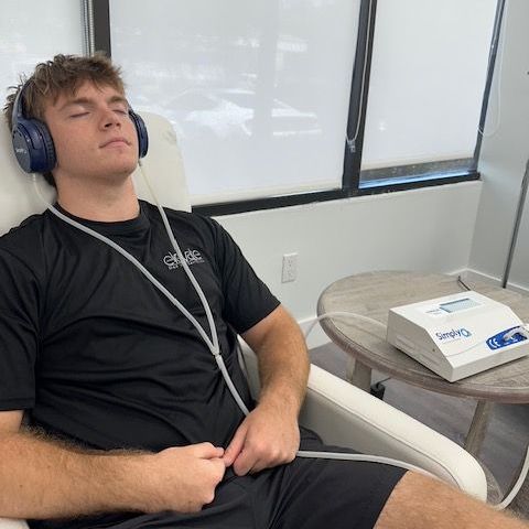 A man wearing headphones is laying in a chair with his eyes closed
